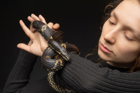 Jovem mulher segurando cobra listrada preta