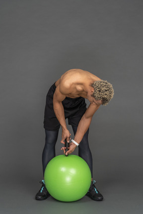 Shirtless man inflating a fitness ball