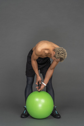 Hombre sin camisa inflando una pelota de fitness