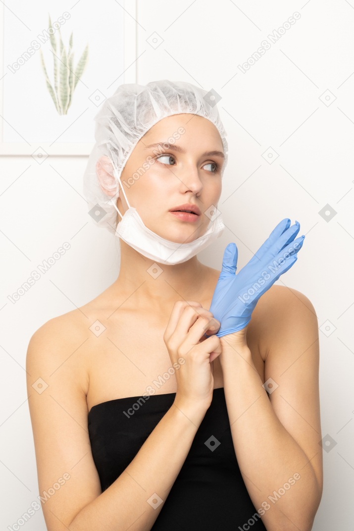 Young woman in scrub cap putting on glove