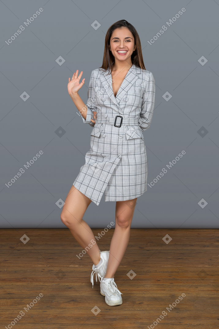 Smiling young brunette woman waving hello