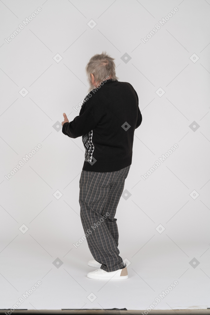 Vista traseira de um homem idoso apontando para fora