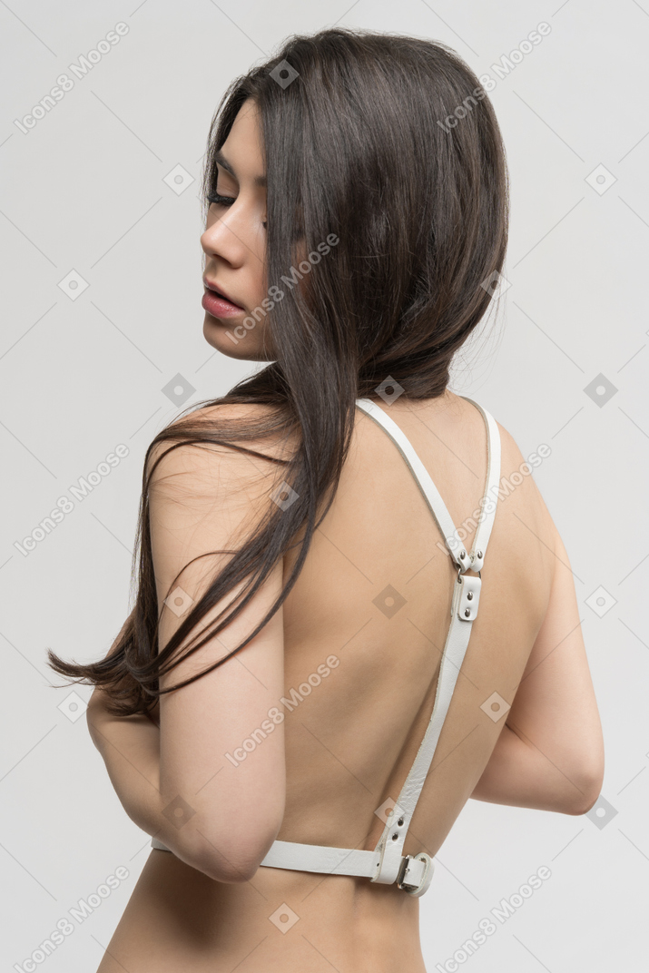 Three-quarter back view of sexy young woman in harness