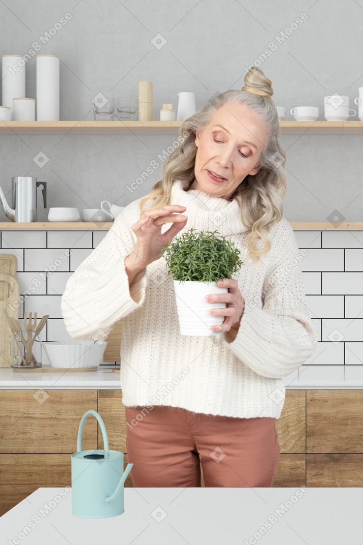 A woman holding a potted plant in a kitchen