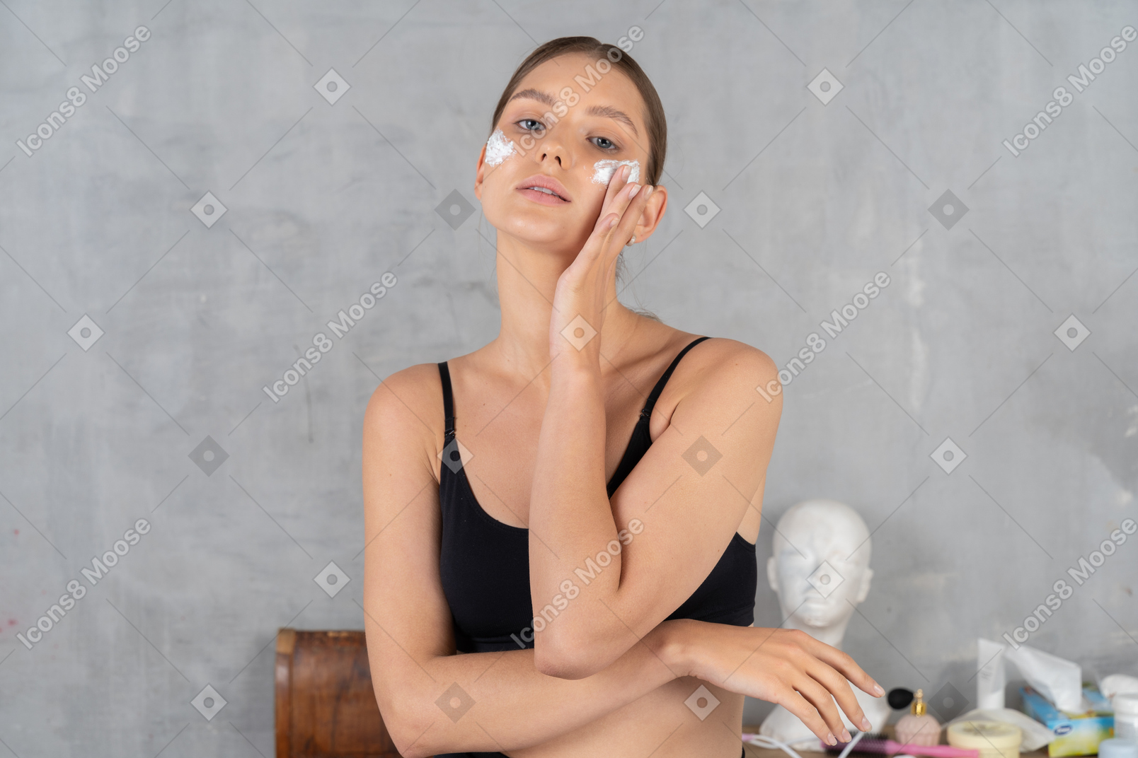 Young woman posing with face cream on her cheeks