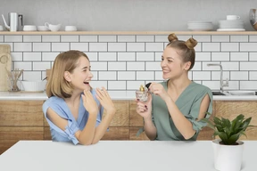 Two women sitting at a table and trying perfume