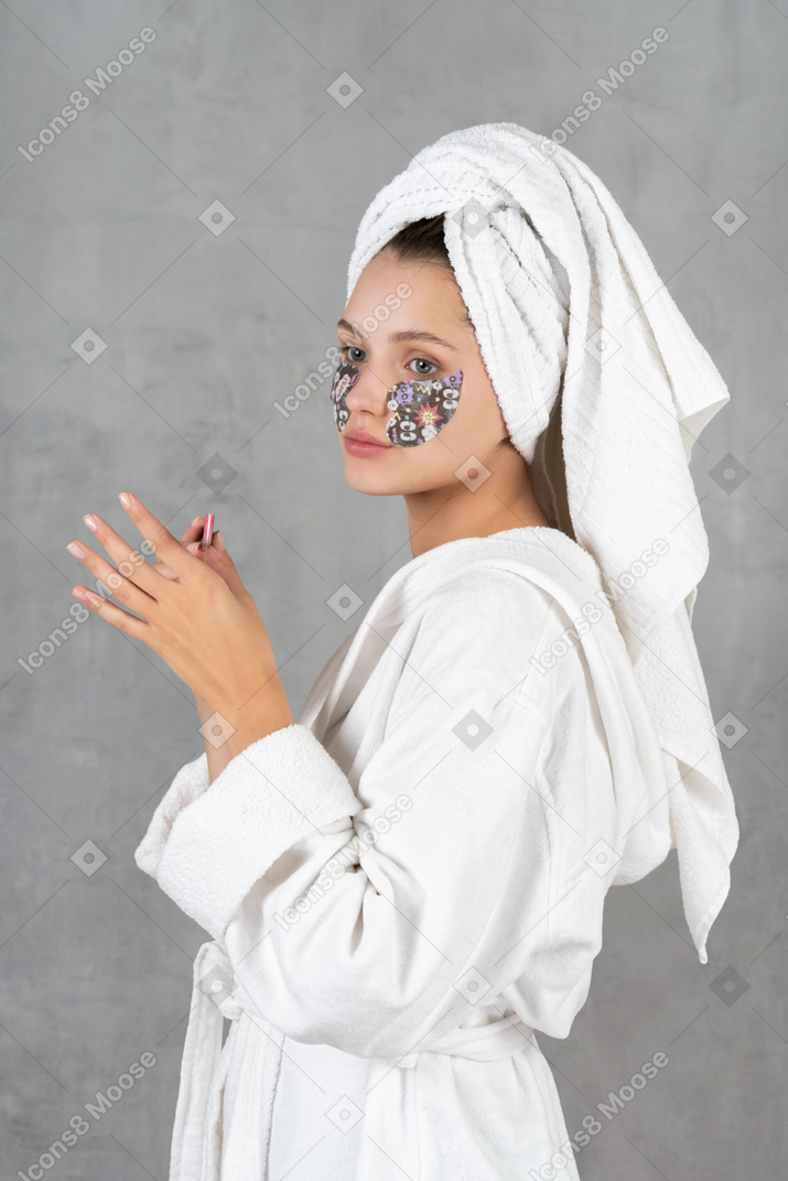 Side view of a woman in bathrobe filing her nails