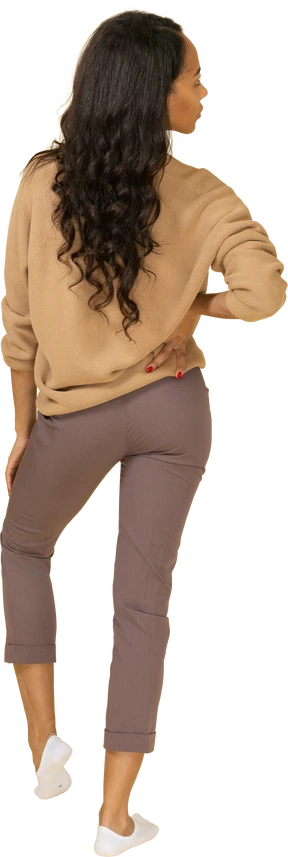 Back view of a dark-skinned young lady putting hand on hip while looking aside