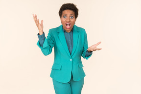 Black woman with a short haircut, wearing all blue, standing against a plain pastel background, looking emotional