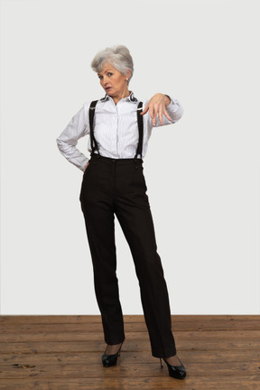 Vista frontal de una anciana en ropa de oficina mostrando un gesto para salir