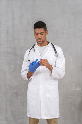 Male doctor in white coat taking off his gloves