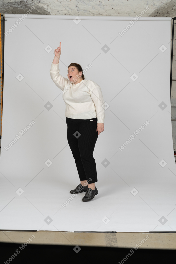腕を上げて立っているカジュアルな服装のプラスサイズの女性の正面図