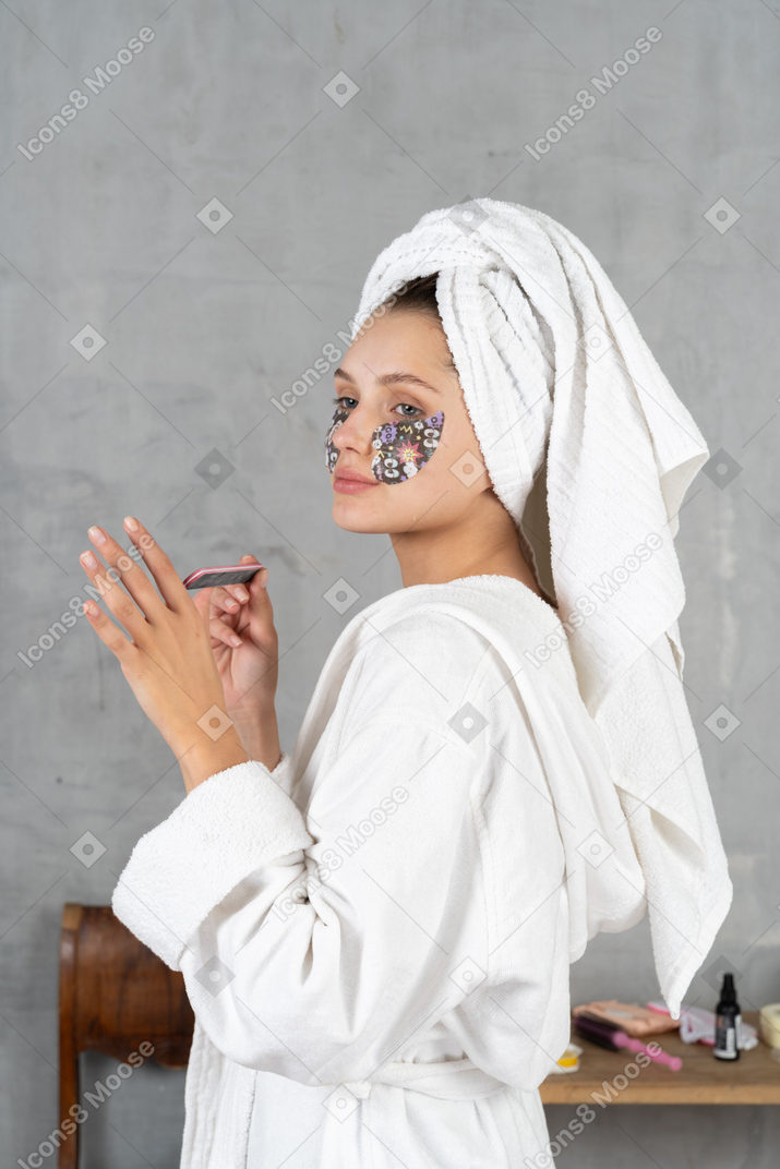 Side view of a woman in bathrobe filing her nails
