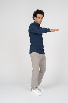 Vista frontal de um homem com roupas casuais apontando com a mão