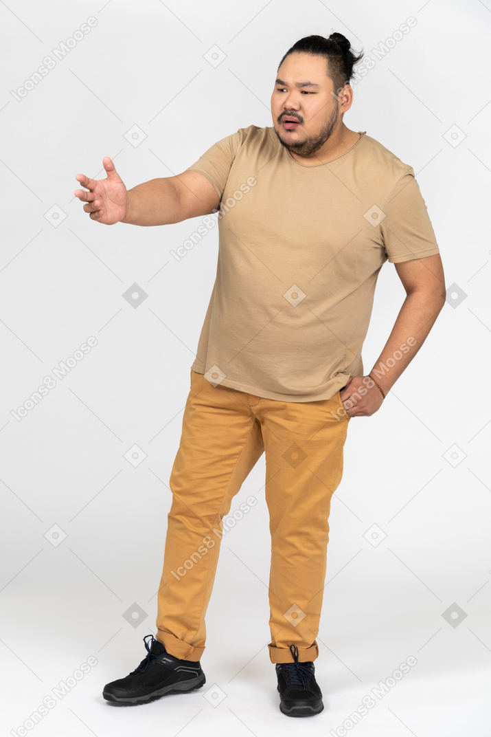 Annoyed young man pointing sideways with a hand