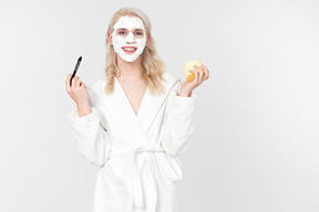 A good looking blond-haired young man in a white bathrobe, being in the process of his beauty care routine