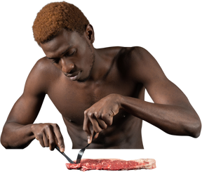 Vista frontal de um jovem afro cortando carne