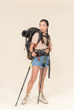 Joven excursionista mujer caminando con bastones de trekking