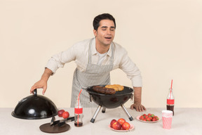 Jovem homem caucasiano cheirando churrasco ele está cozinhando