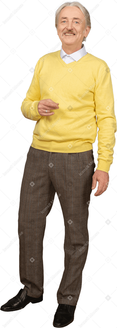 Front view of a gesticulating old man wearing yellow pullover and looking at camera while smiling