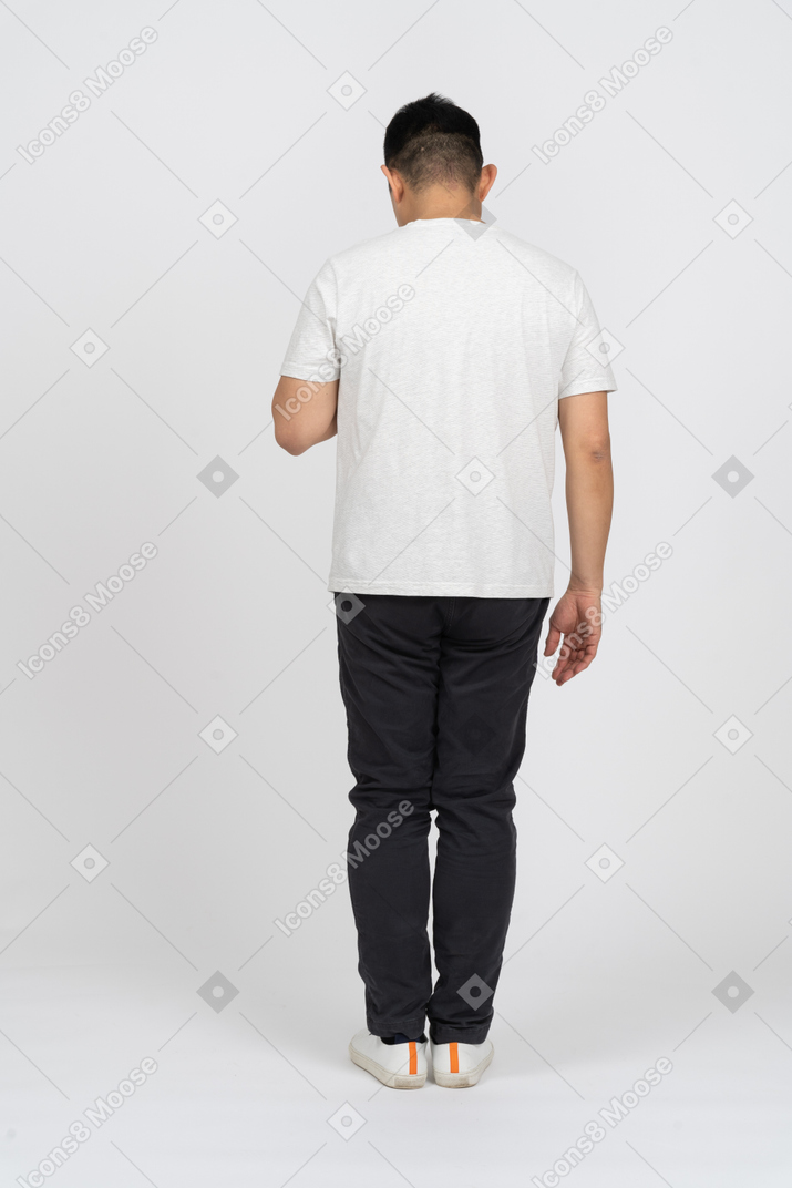 Man in casual clothes standing back to camera and looking down