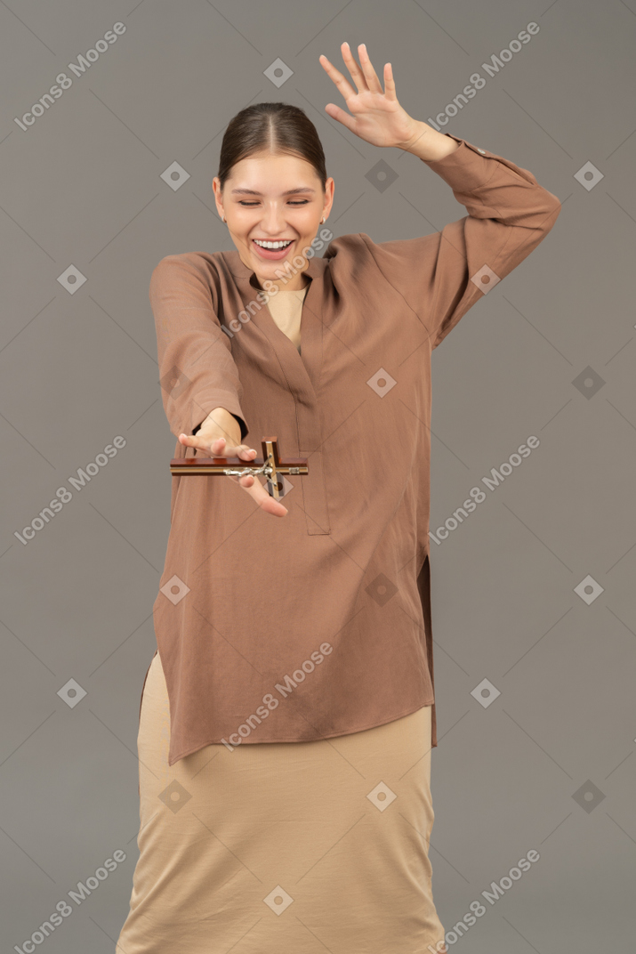 Young christian woman holding a cross and laughing
