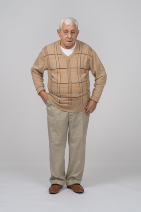 一位身穿休闲服的老人手放在口袋里站着的正面图