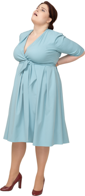 Vista frontal de uma mulher de vestido azul sofrendo de dor na região lombar