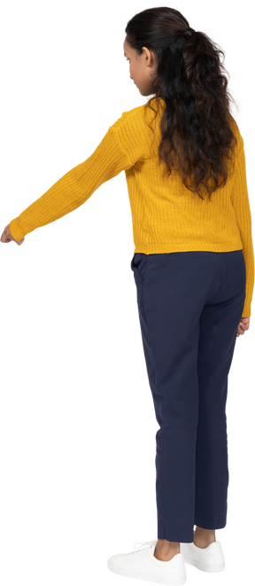 Rear view of a girl in casual clothes standing with extended arm