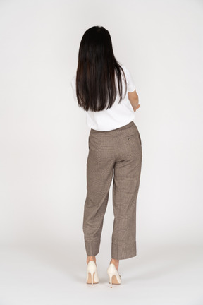 Vista posteriore di una giovane donna in calzoni che attraversano le mani