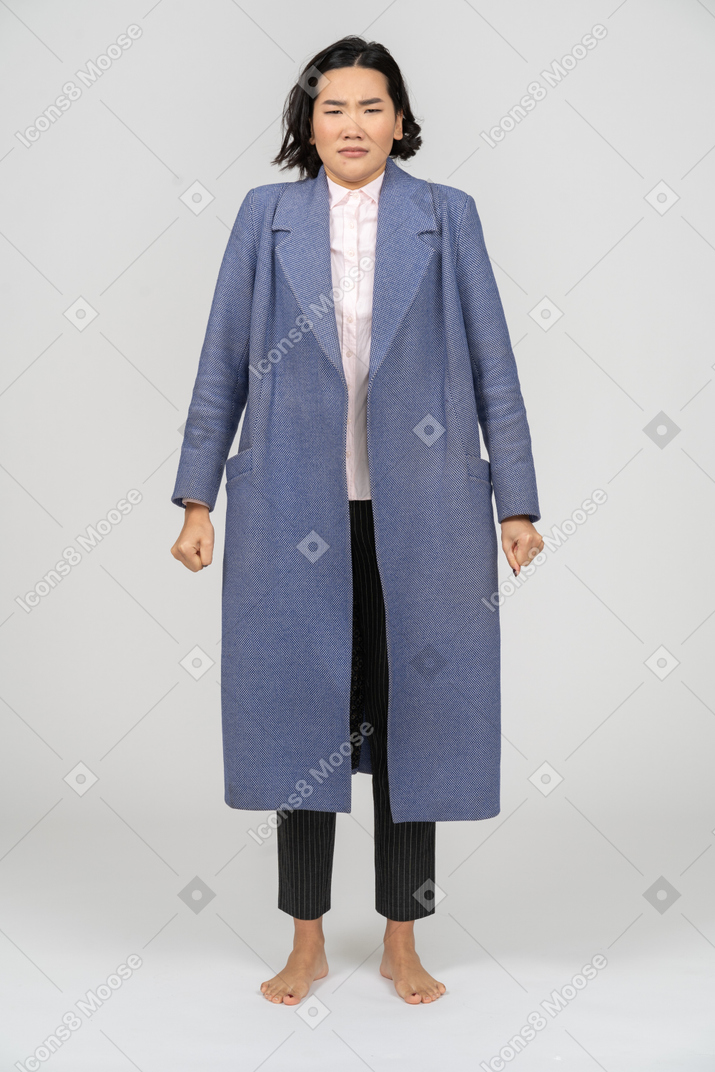 Upset woman in a coat standing with clenched fists