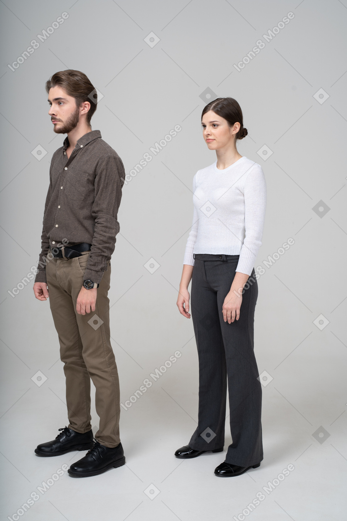 Vista lateral de um jovem casal com roupas de escritório, parado