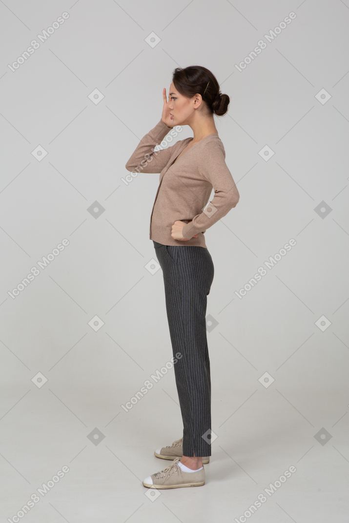 Vista lateral de uma jovem senhora de pulôver e calça tocando a cabeça