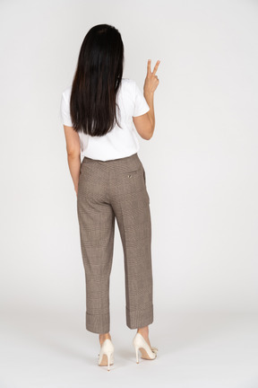 Vista traseira de uma jovem de calça, mostrando o símbolo da paz