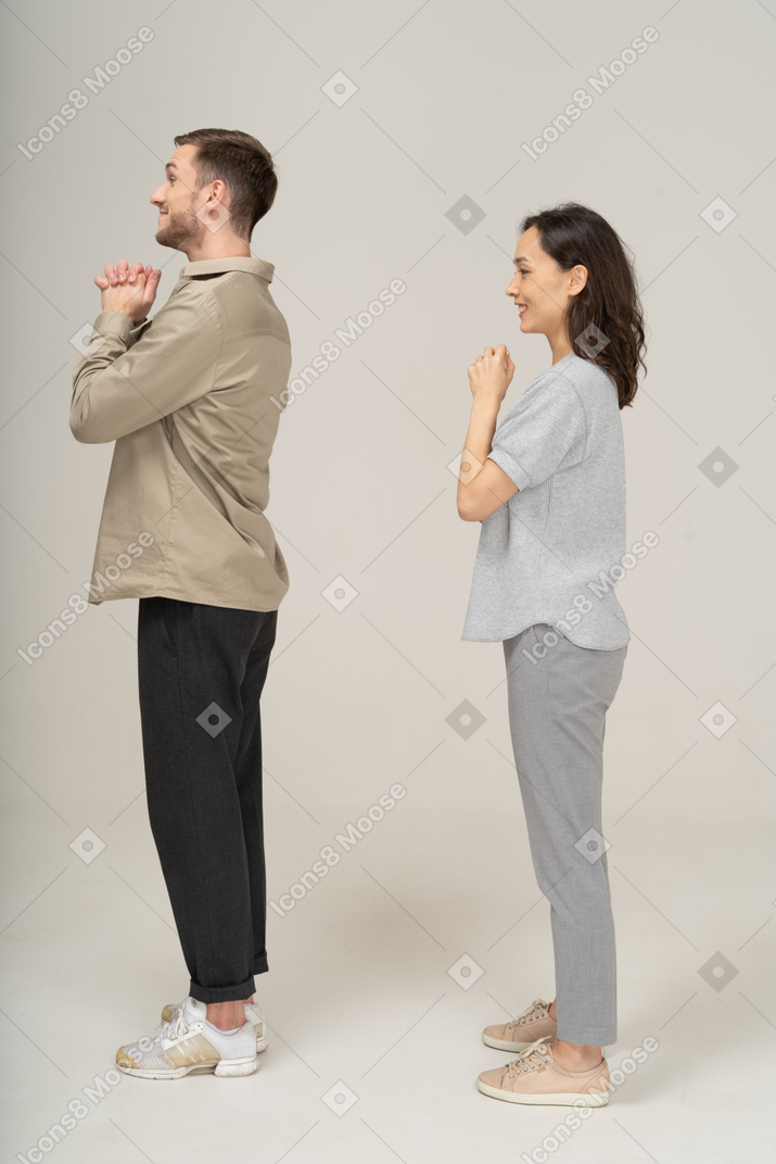 Side view of young couple portraying please gesture