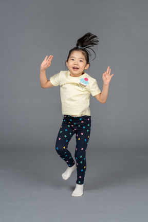 Девушка прыгает на одной ноге с поднятыми руками