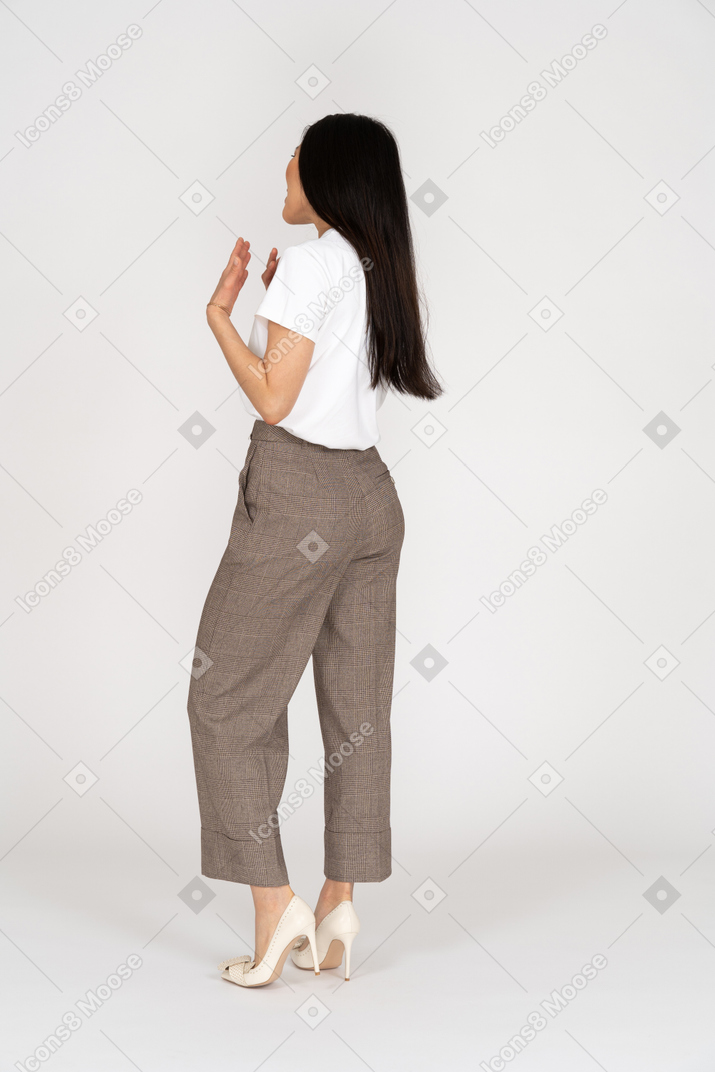 Three-quarter back view of a shouting gesticulating young lady in breeches and t-shirt