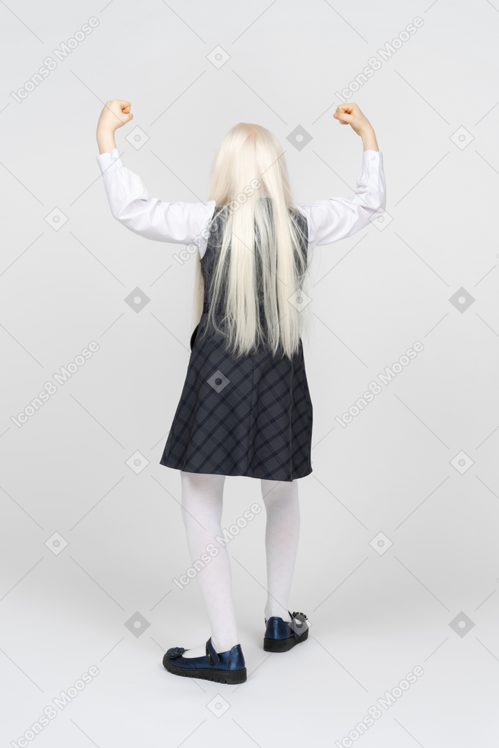 Back view of a schoolgirl holding her hands up