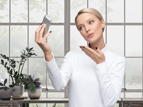 A woman is holding a phone and sending air kiss