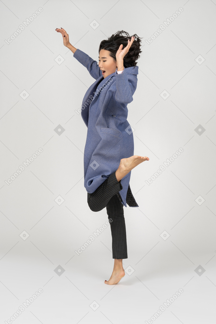 Side view of woman jumping on one leg