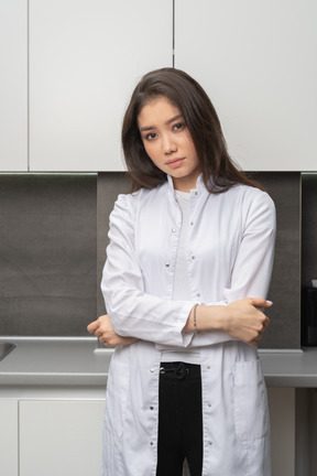 Front view of a serious female doctor crossing hands and looking at camera