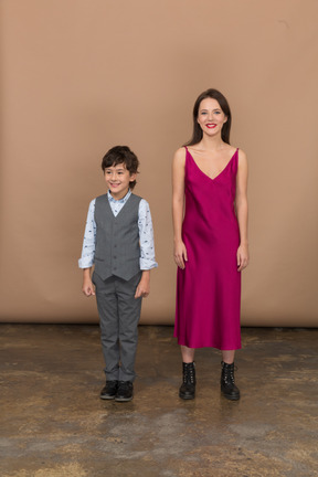 Mulher de vestido vermelho em pé com um menino sorridente