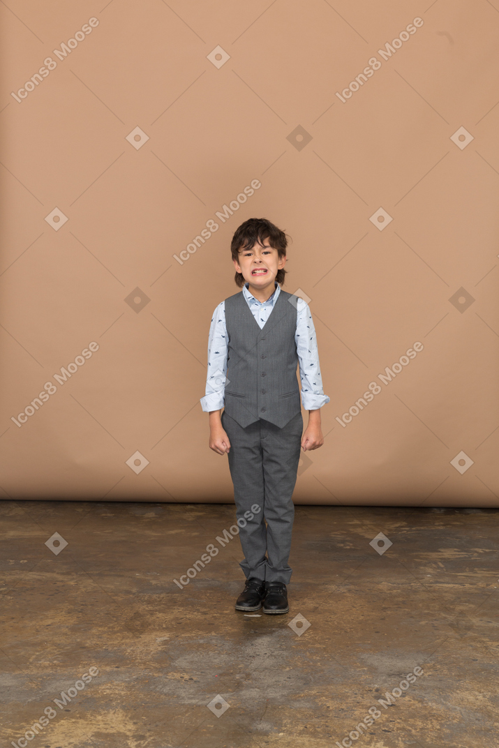 Front view of a cute boy in suite looking at camera and showing teeth