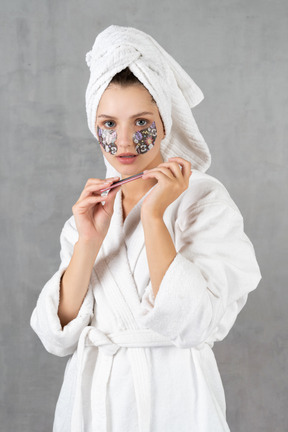 Woman in bathrobe filing her nails