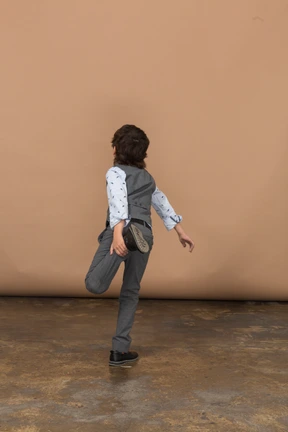 Rear view of a boy in suit standing on one leg