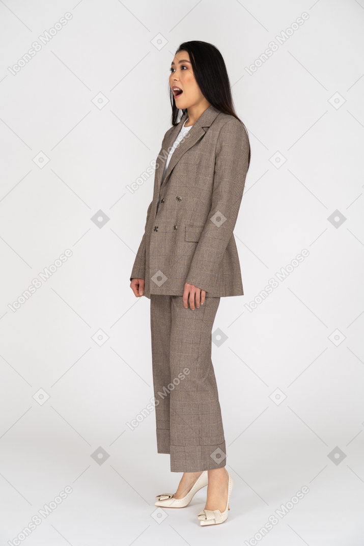 Вид в три четверти удивленной молодой леди в коричневом деловом костюме
