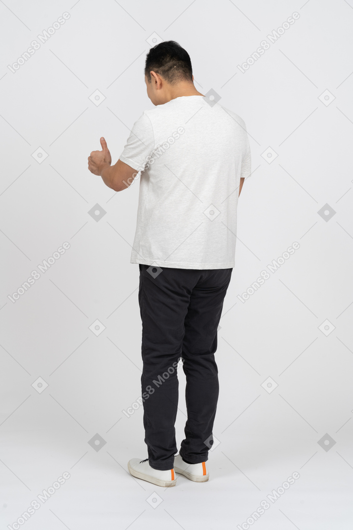 Homem em roupas casuais em pé de volta para a câmera e aparecendo o polegar