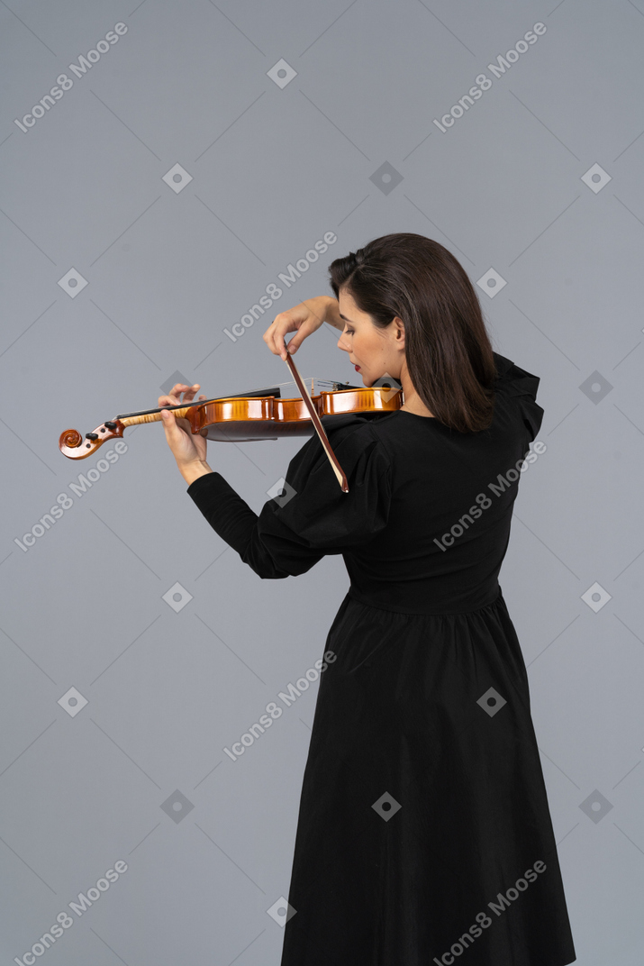 Close-up de uma jovem de vestido preto tocando violino