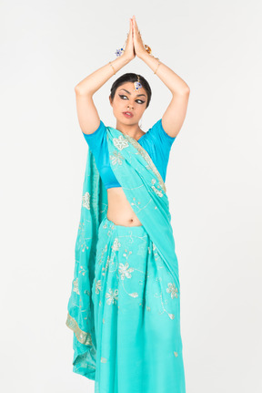 Joven mujer india en sari azul de pie en posición de baile