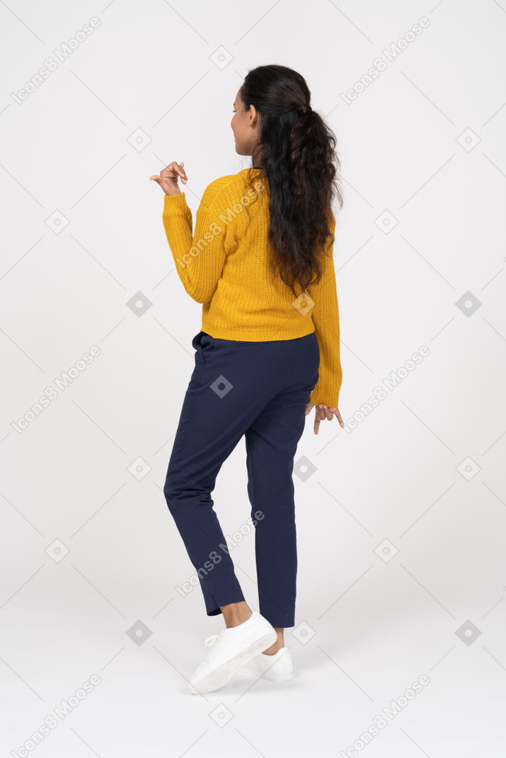 Vista posteriore di una ragazza in abiti casual che fa un gesto rock